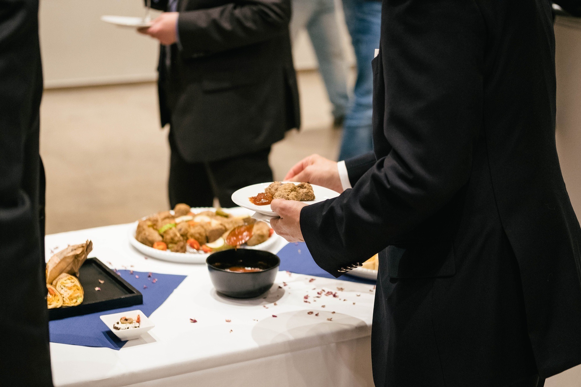 People in suits serve themselves at the buffet and eat delicious food at a business event